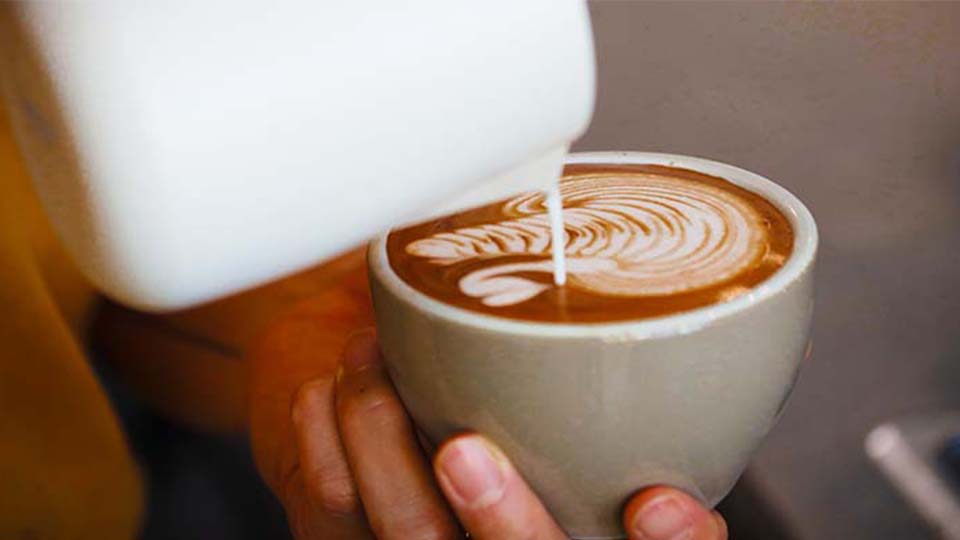 Barista pours milk into coffee