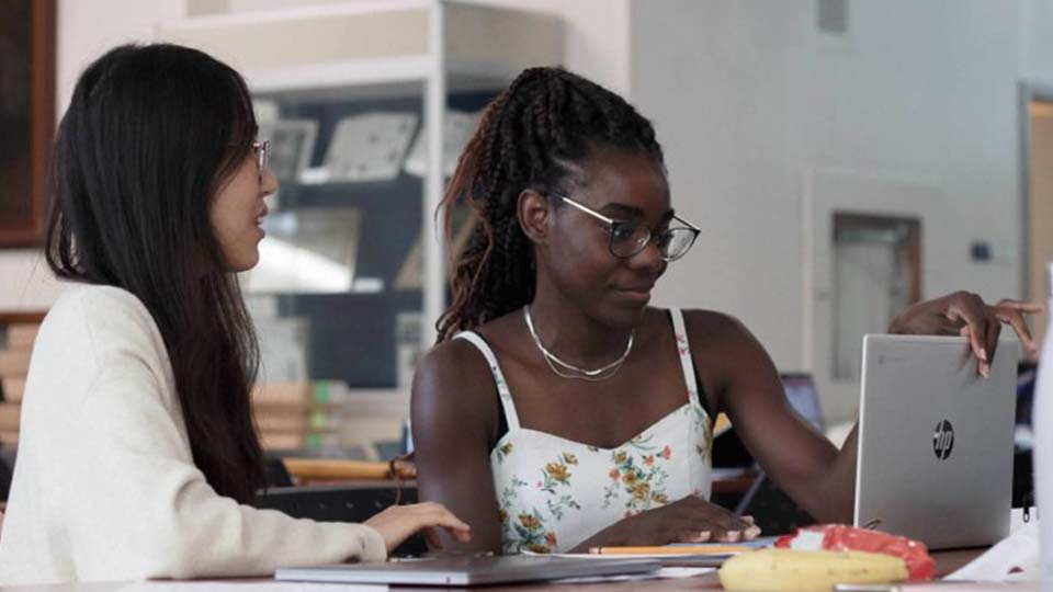 Two female students studying in front of a laptop