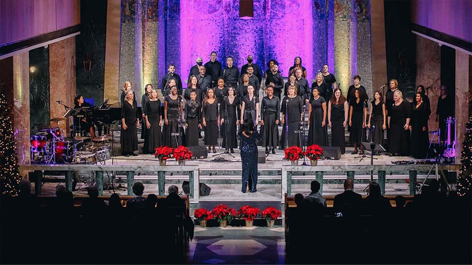 A group of men and women dressed in black representing the Tyndale Community Choir on stage inside the chapel