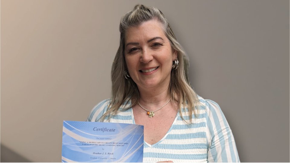 Dr. Heather Birch holds up best paper award certificate