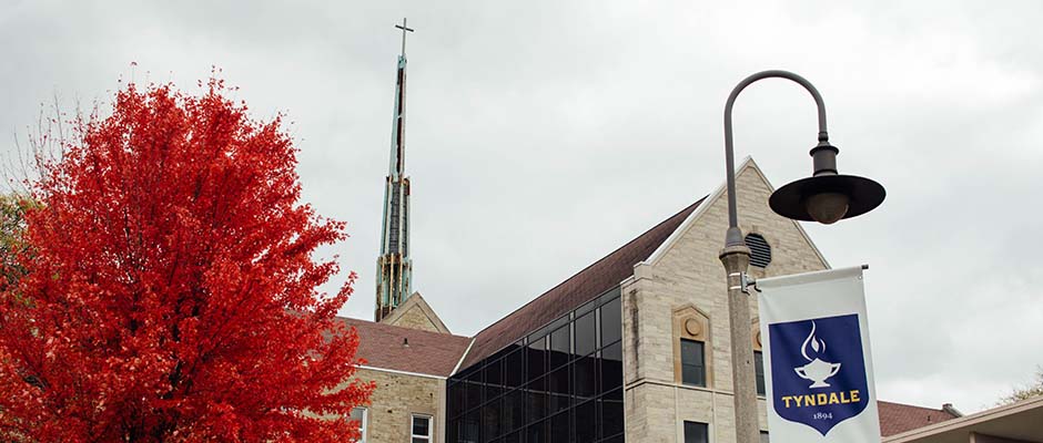 Lightpost with banner infront of the Tyndale University campus entrance