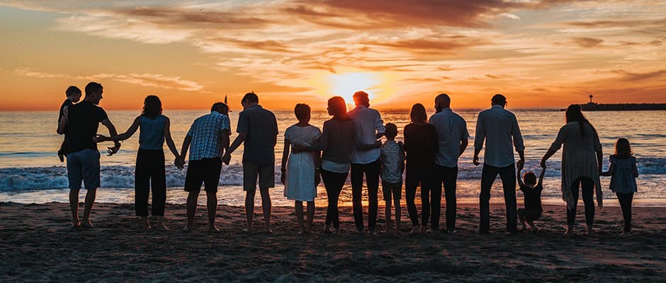 Family standing on the beach at sunset