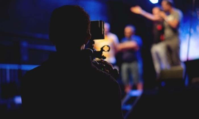 A videographer taking a video of people on stage