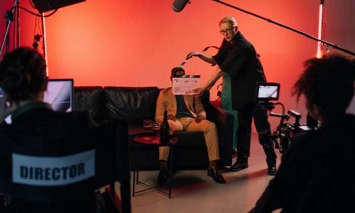 A man giving directions on a chair with surrounding equipment and people