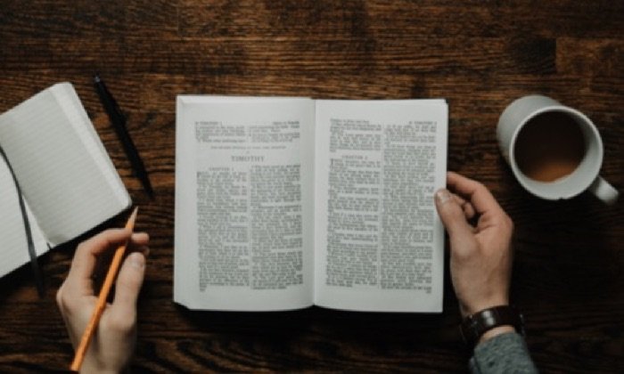 Someone studying a book at a table with a top-down view