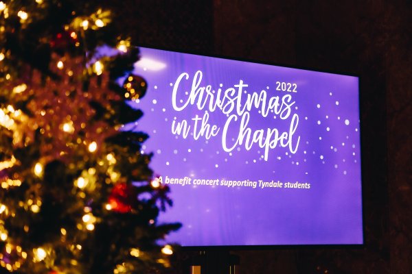 Christmas In the Chapel Main Projection Slide beside Christmas Tree