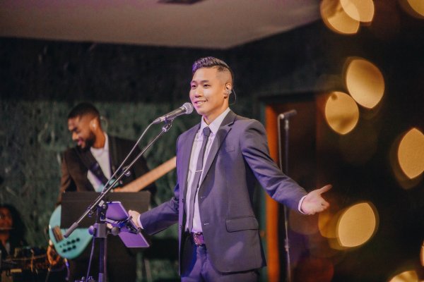 Darrick Tam singing with arms wide open at centre stage of the chapel