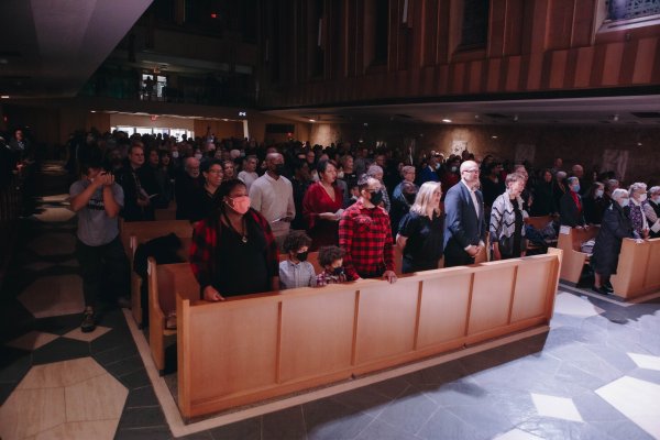 Attendees standing up singing and worshipping in the chapel pews