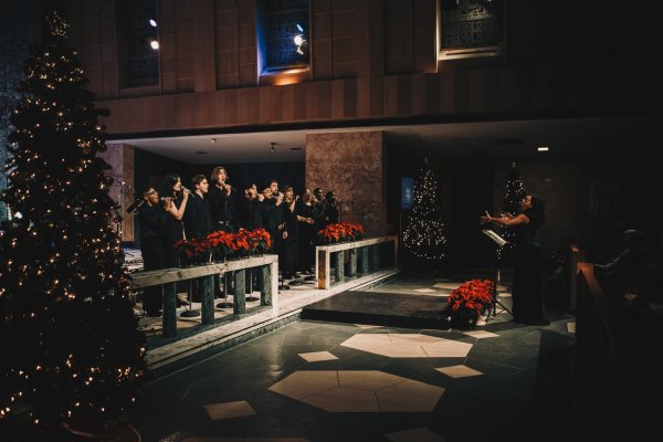 A group of singers on stage with a lead conductor 