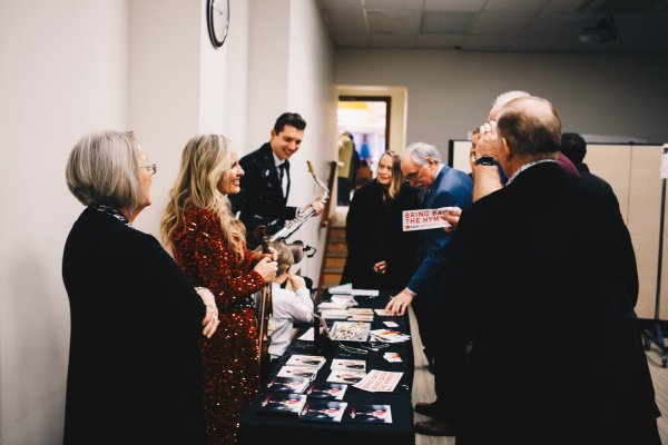 A group of men and women surrounding a table with gifts and stationary items