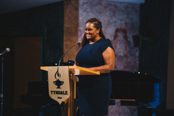 Woman speaks at podium, Natasha Daley gives speech