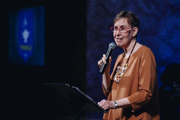 Dr. Marjory Kerr smiles at the podium giving an introductory speech