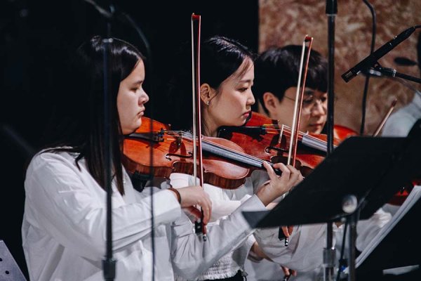 Two females and one male playing string instruments