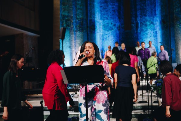 Choir leader singing while the choir joins her on stage