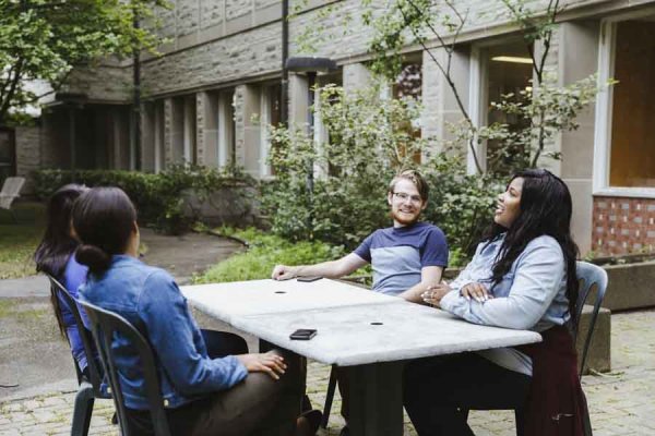 Students sitting at an outdoor table in one of the Tyndale courtyards