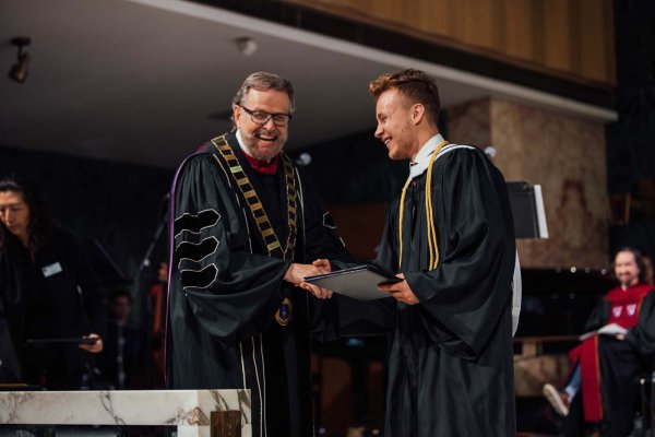 President Nelson presenting the graduation certificate to a graduate